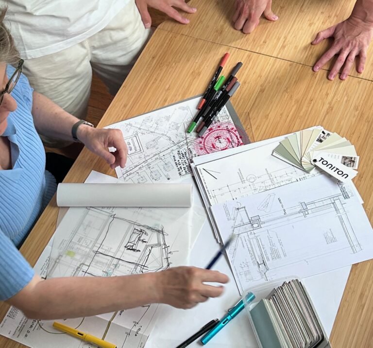 Architect presenting Feng Shui solutions and corrective measures to client over architectural drawings and colour samples